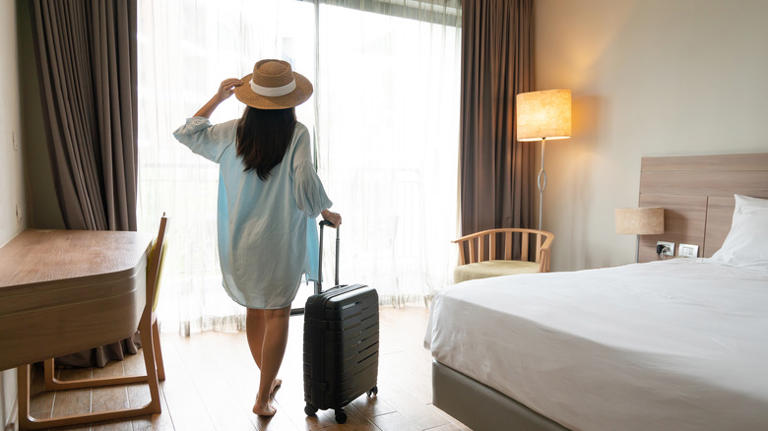 Woman with suitcase in hotel bedroom