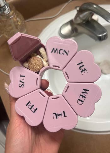Reviewer holding the pink version with one of the capsules open revealing medication