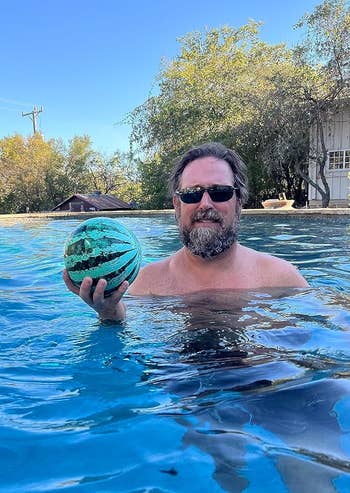 an adult holding the watermelon pool ball in one hand