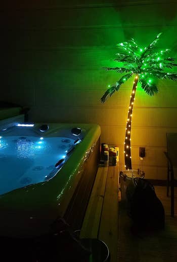 Artificial palm tree with lights next to an outdoor hot tub, suggesting tropical ambiance for home decor