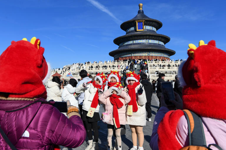 Tourists from Malaysia pose for photos wearing dragon themed hats at the Temple of Heaven in Beijing, China, in January. Photo: Xinhua