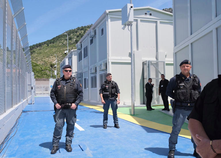 Policemen guard a reception centre for migrants at the port of Shenjin (Vlasov Sulaj/AP)