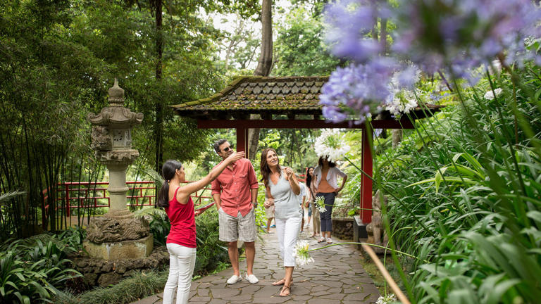 Globus independent travelers tour an Asian garden with a guide.
