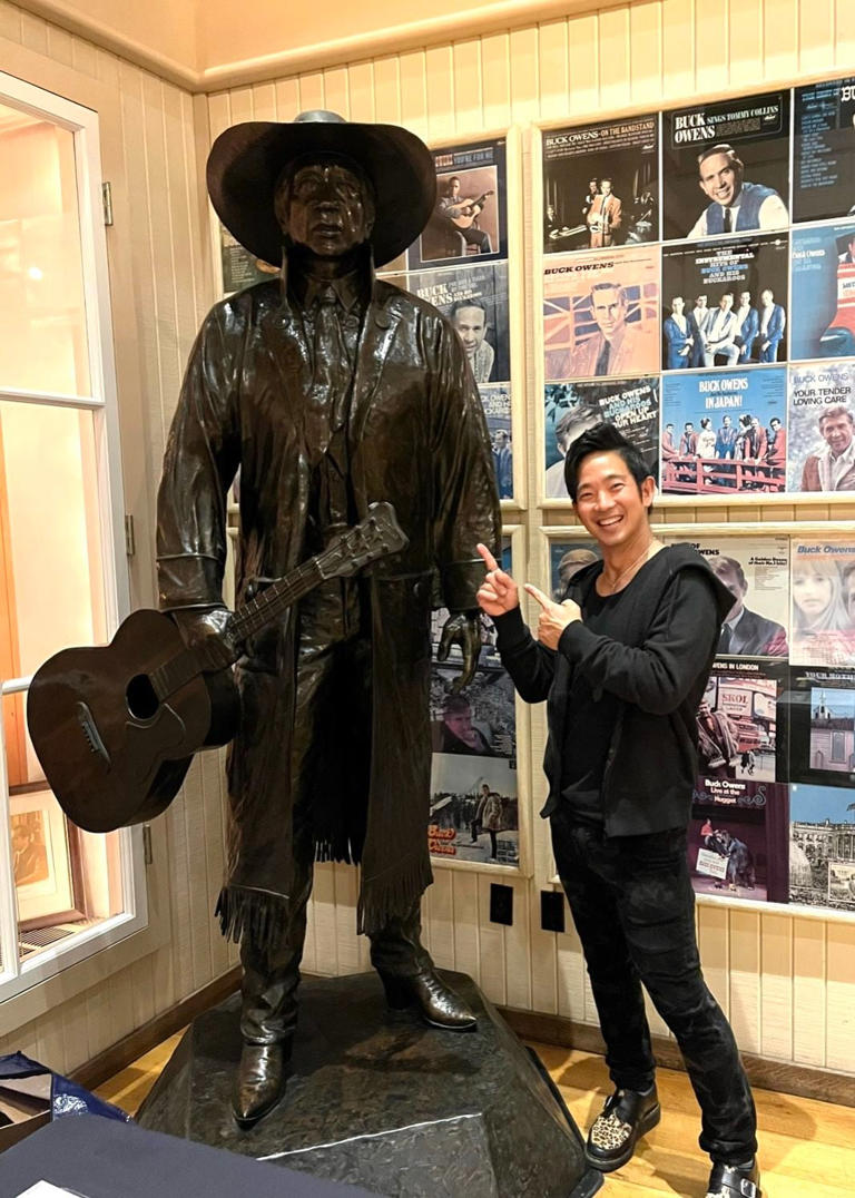 Jake Shimabukuro next to a bronze statue of Buck Owens in Bakersfield, Calif.