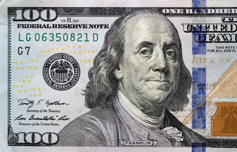 A stock image of a $100 bill. An authentic $100 note comes with security features that can be seen when held up to a light.