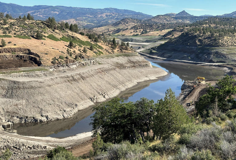 The Klamath River flows toward the former Iron Gate Dam outside the town of Hornbrook in Northern California. Heavy machinery is scooping the leftover dirt to remove it from the site.