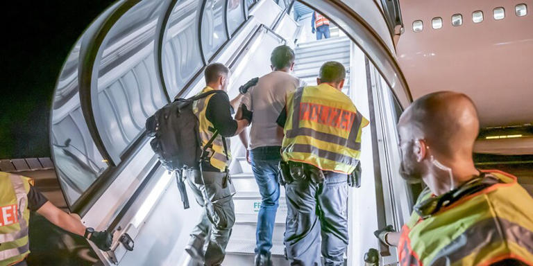 Polizeibeamte begleiten einen Afghanen auf dem Flughafen Leipzig-Halle in ein Charterflugzeug. Michael Kappeler/dpa/Archivbild
