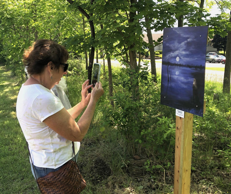Jan Romeiser enjoys a painting along the Ontario Pathways trail in Canandaigua as part of the opening of a joint public arts project with the trails organization and Ontario County Arts Council.