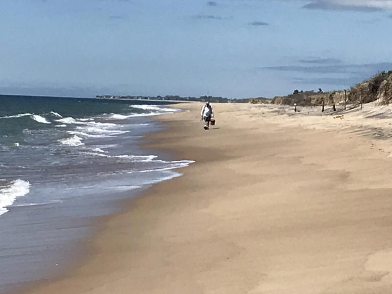 A lone fisherman walks southeast on East Beach toward the Charlestown Breachway.