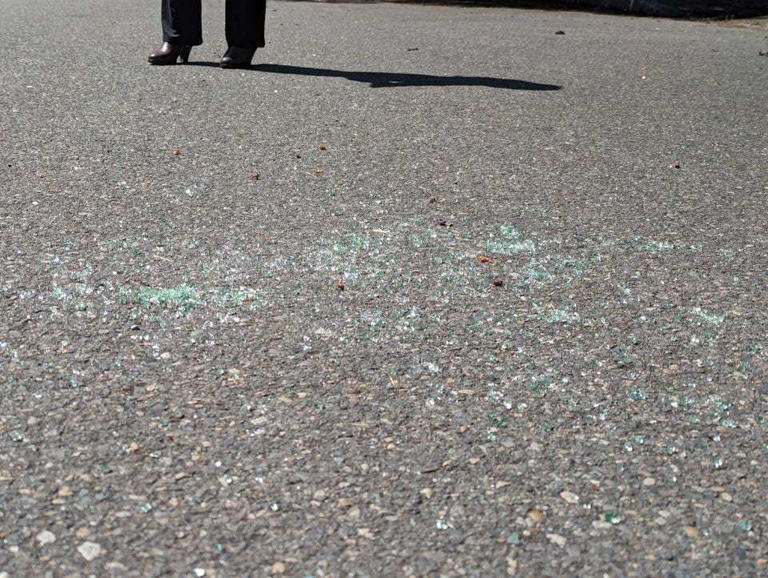 Glass shards remained at the crime scene after a rideshare driver was shot to death and his teenage passenger was critically injured.