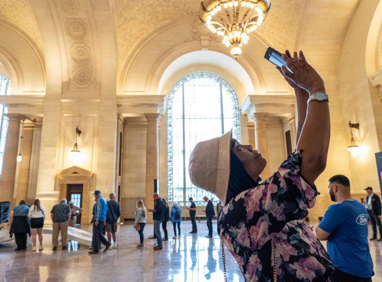 Algeria Calloway, of Detroit, takes photos while looking over the main lobby during tours of the Michigan Central Station in Detroit's Corktown neighborhood on Friday, June 7, 2024.