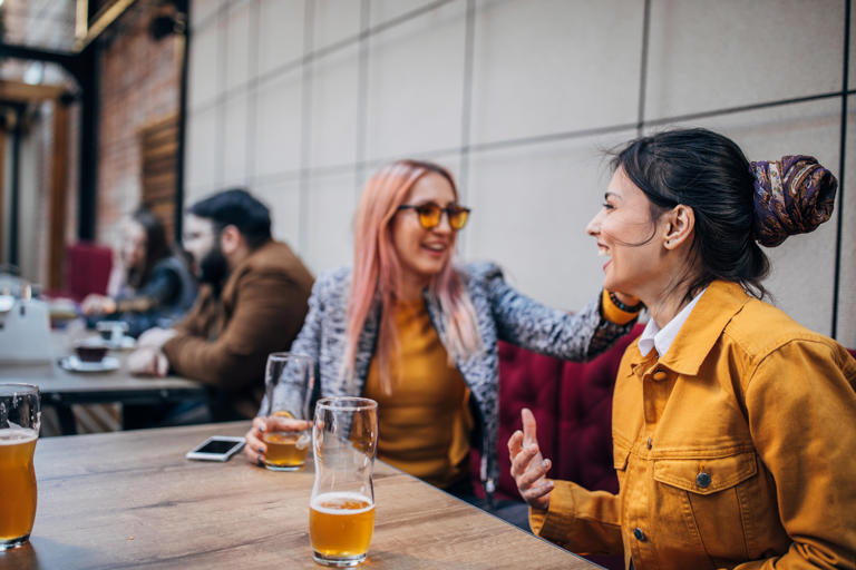 Dos amigas tomando una cerveza en la terraza de un bar