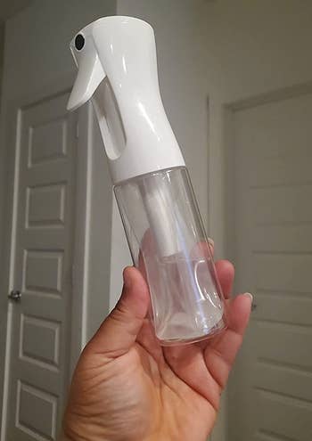a reviewer holding the spray bottle filled with water