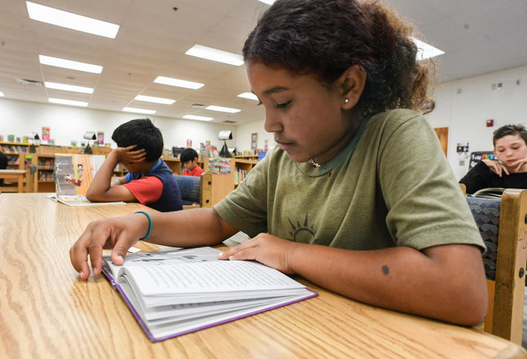 Third grade student Amaya Torrez, 8, reads about dancing while inside Weatherbee Elementary’s multimedia center on Tuesday, April 30, 2024, in Fort Pierce. "I like to read about dance," Amaya said. "It keeps me calm and it keeps me focused and peaceful."