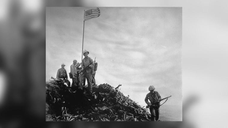 Sgt. Ernest Boots Thomas stands in front of the first flag raised on Iwo Jima Feb. 23, 1945.