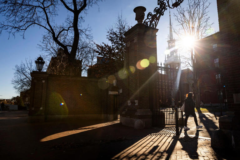 A pedestrian walks through an entrance on Harvard University’s campus in Cambridge, Mass., Dec. 12, 2023.