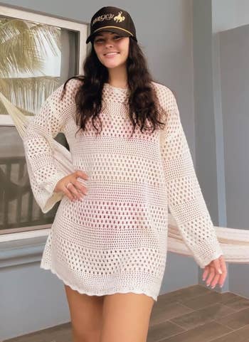 reviewer in a white crocheted swimsuit cover up derss