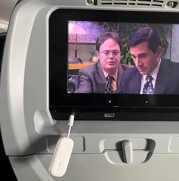 the small white device plugged into a screen on a plane via USB
