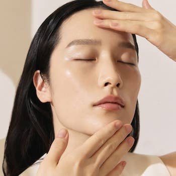 Person with eyes closed applying skincare product to face. Image used in a shopping article