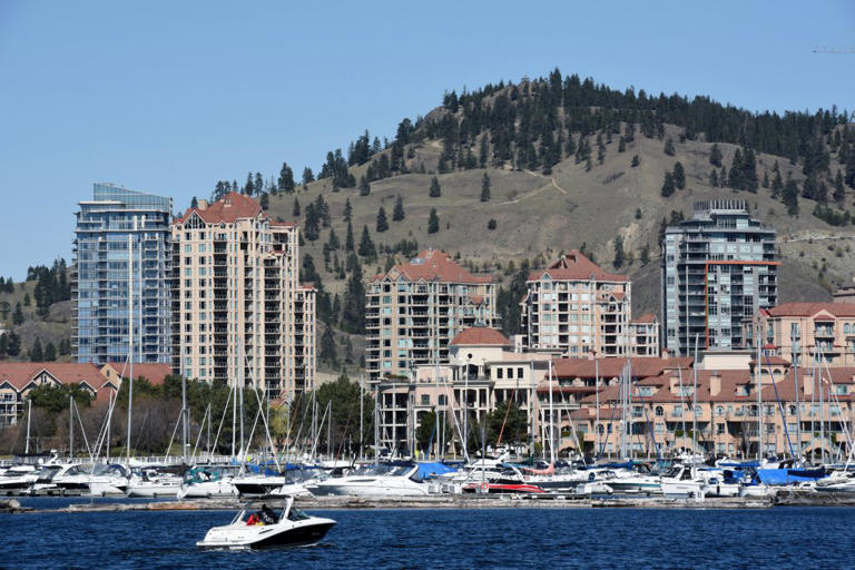Boats float on Okanagan Lake with Kelowna's skyline in the background.