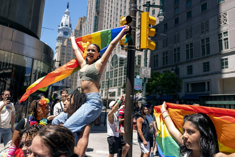 Kimberly Orozco rides on the shoulders of Keven Collins as they march up Market Street on June 5, 2022 during the city's 50th annual Pride celebration.