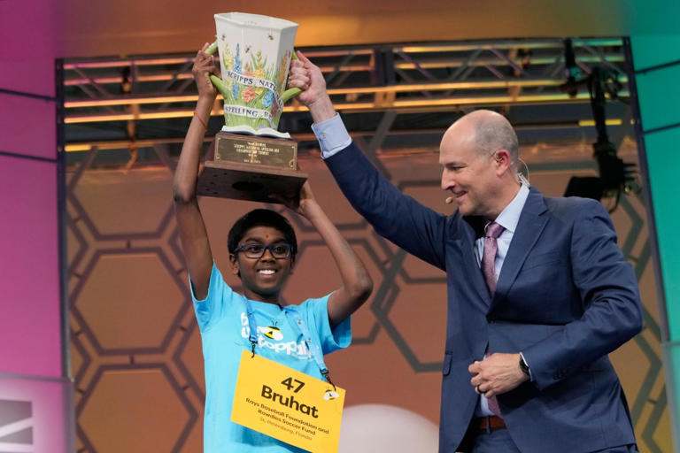 Bruhat Soma, 12, of Tampa, Fla., accepts the trophy from E.W. Scripps Company president and CEO Adam Symson after winning the Scripps National Spelling Bee, in Oxon Hill, Md., Thursday, May 30, 2024. (AP Photo)