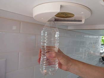hand holding a water bottle using the opener to get the cap off