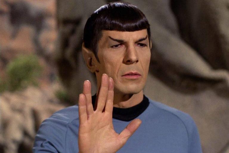 <p>The origin of Spock's iconic salute can be traced to Leonard Nimoy's creative inspiration. Drawing from his Jewish heritage, Nimoy crafted the distinctive gesture by adapting the hand sign used in a sacred Hebrew blessing. </p> <p>The open hand, with fingers separated in a "V" shape, became synonymous with Vulcan culture and a beloved symbol for <i>Star Trek</i> fans worldwide.</p>