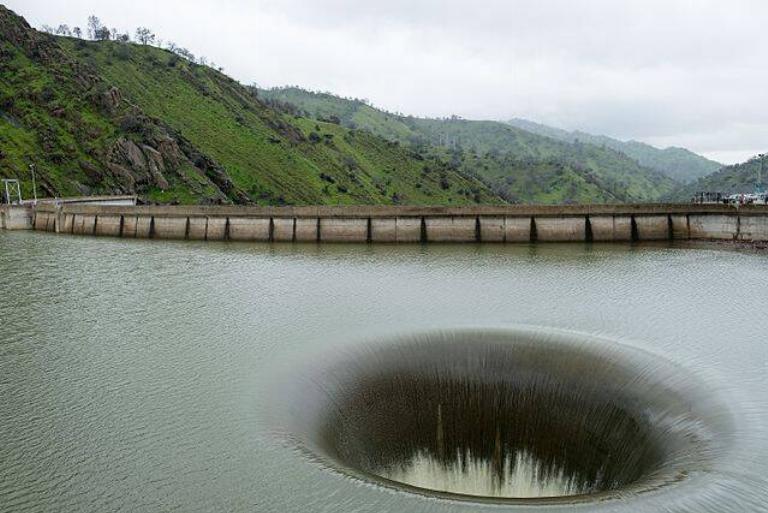 <p>You can find Monticello Dam in Napa County, California. Construction started in 1953 and ended in 1957. This is a human-made hole and it's used when the reservoir reaches full capacity. The reservoir provides water to San Francisco's North Bay area.</p> <p>The hole itself can take in 48,000 cubic feet of water per second! That doesn't sound like anything anybody should be swimming in. A woman drowned after she was sucked into the spillway back in 1997 and they banned swimming in it ever since.</p>