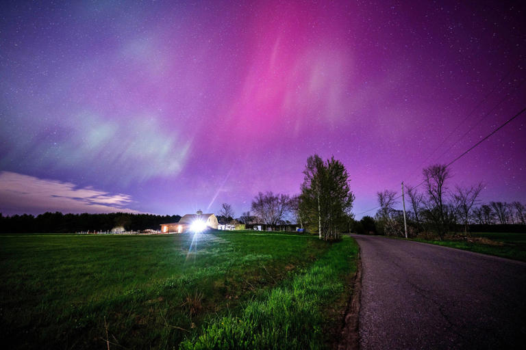 The aurora borealis fills the sky with pink and blue waves over a farmhouse in Mercer, Maine on May 11, 2024.