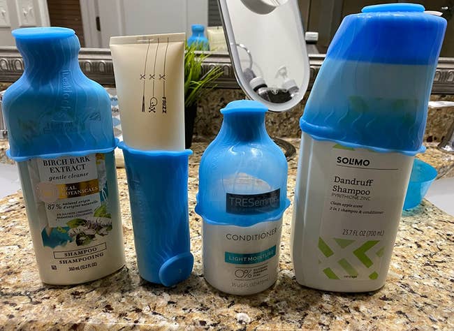 Blue stretchy silicone leak protectors over the lids of shampoo and conditioners