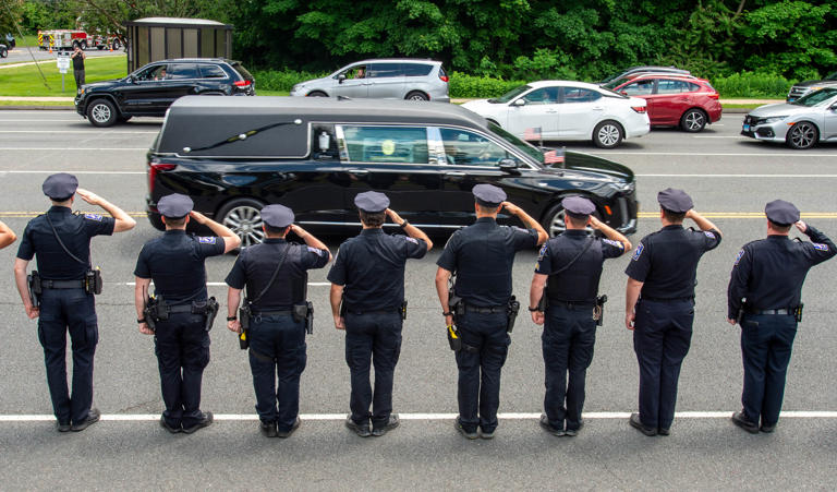 Members of the West Hartford Police Department salute as the late Connecticut state police TFC Aaron Pelletier is escorted from the Office of the Chief Medical Examiner in Farmington to Della Vecchia Funeral Home in Southington on Friday, May 31, 2024.