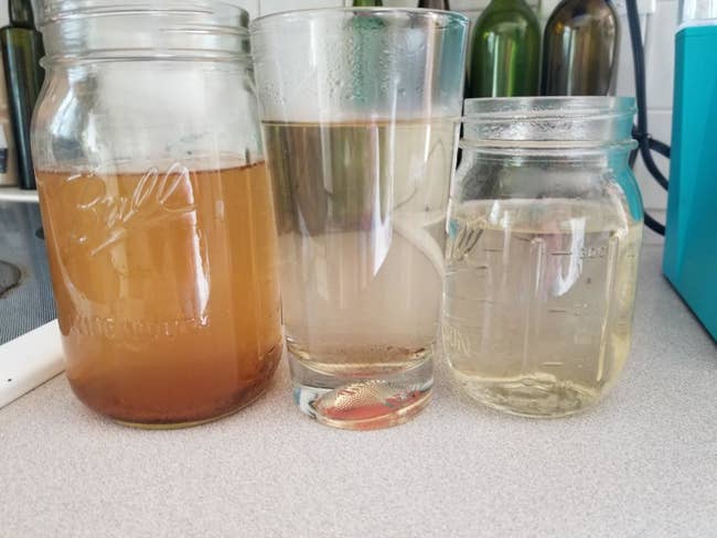 reviewer photo of the water that came out of their keurig after using the k-cup cleaning pod and you can see that the original brown water gets cleaner and clearer after each cycle of using the cleaning cup