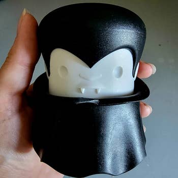 a reviewer hand holding the vampire-shaped garlic crusher
