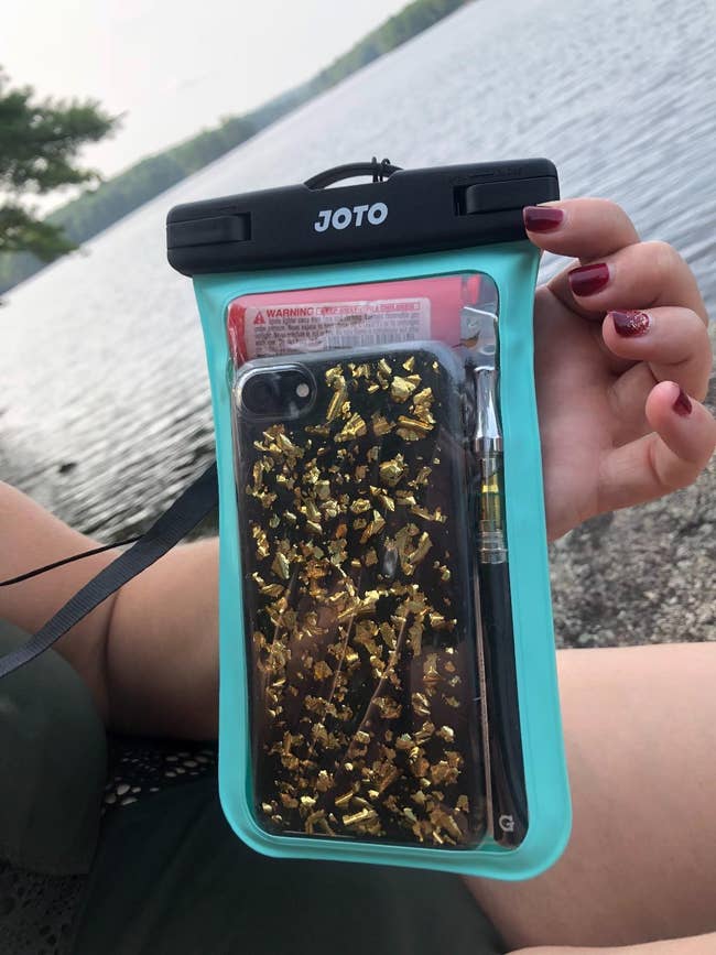 reviewer holding the case with their phone in it next to the water