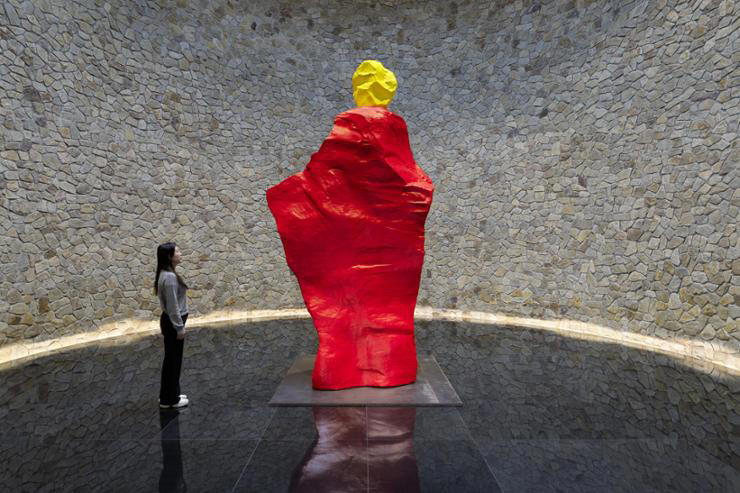 Ugo Rondinone's 'yellow red monk' (2021) stands guard at the schist-encased Nam June Paik Hall in Museum SAN in Wonju, Gangwon Province, as part of the Swiss artist's most comprehensive exhibiiton to date in Korea titled 'BURN TO SHINE.' Courtesy of Museum SAN