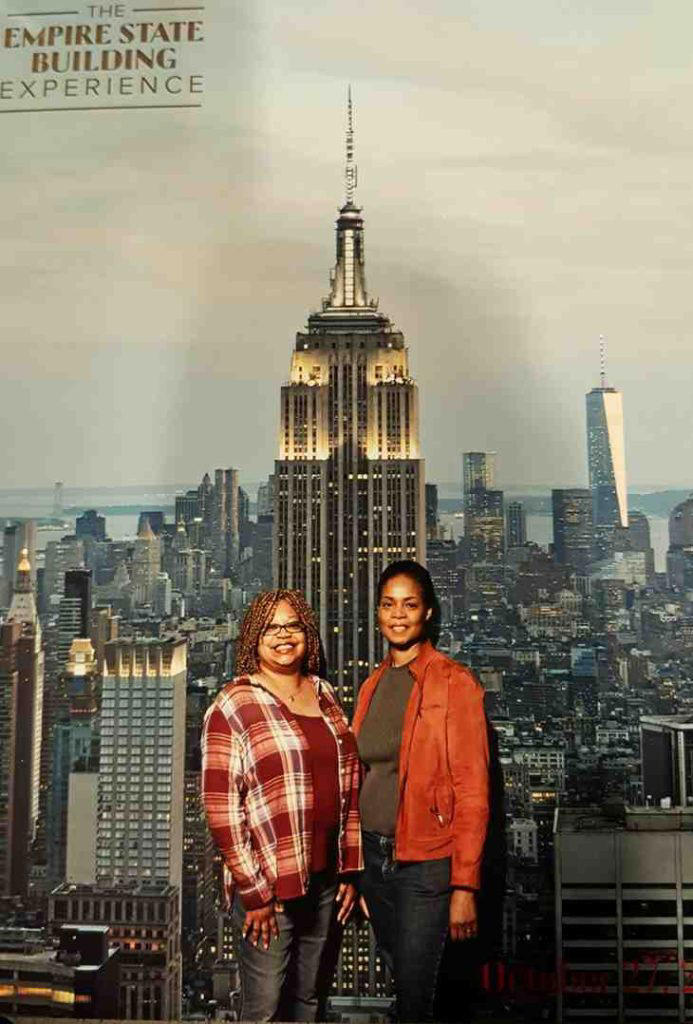 two women standing in front of image of the Empire State Building