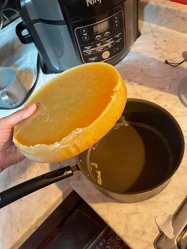 Reviewer holding a block of solidified fat over a saucepan