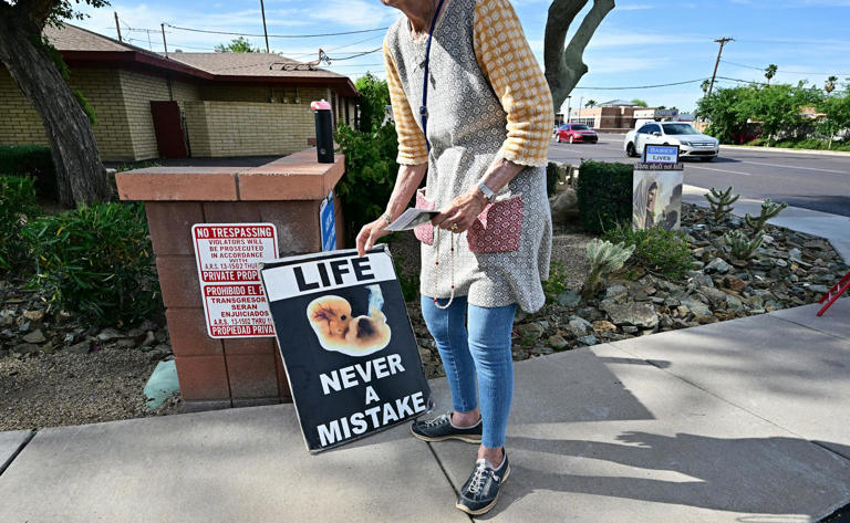 An anti-abortion rights advocate places a sign in front of an abortion clinic in Phoenix on April 18, 2024. 