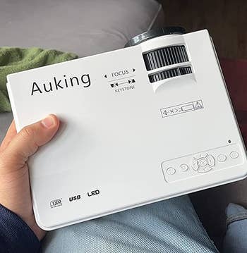reviewer holding the white projector to show scale