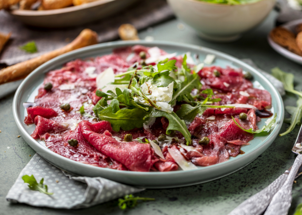 <p>"Carpaccio" is an Italian term for thin slices of raw beef or fish served with a sauce, created in 1950 by Giuseppe Cipriani. The Venetian chef named the dish after the painter Vittore Carpaccio because the red of the beef <a href="https://www.merriam-webster.com/dictionary/carpaccio">matched the colors</a> in the Renaissance paintings, he wrote in his memoir. Cipriani first served carpaccio to a countess who was under a doctor's orders to avoid eating cooked meat. Since then, the term has taken off in the culinary world and evolved to refer to the practice of thinly slicing anything, from fruits to vegetables.</p>