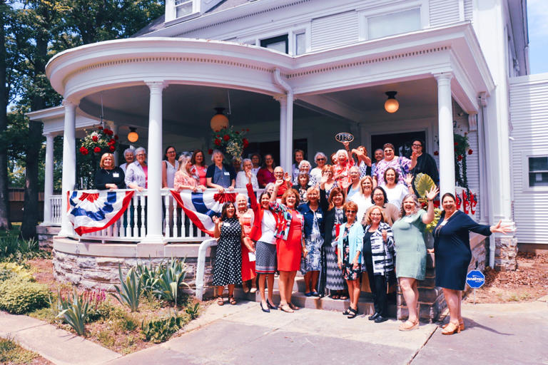 Mary Ellen Withrow, (back row, center), former U.S. treasurer and longtime Marion Women’s Club member, lifts the address plaque placed on the restored front porch at the Marion Women’s Club Home.