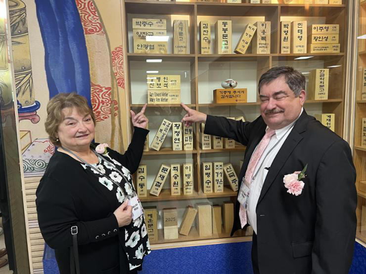 Mary Ann and Gary Mintier point to a plaque bearing their names on a display of donors during a ceremony at the National Library, Courtesy of Mary Ann and Gary Mintier