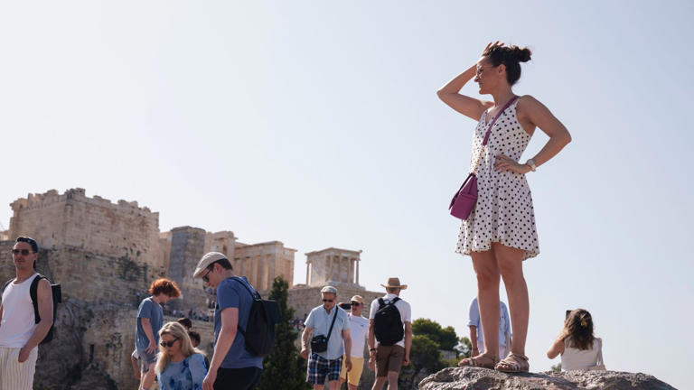 Tourists stand at the Aeropagous hill in front of the ancient Acropolis. Pic: AP.