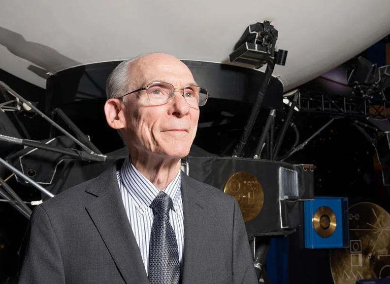 Ed Stone, former director of JPL and project scientist for the Voyager mission, in front of a mock-up of one of the Voyager spacecraft. The golden record is visible over his left shoulder.