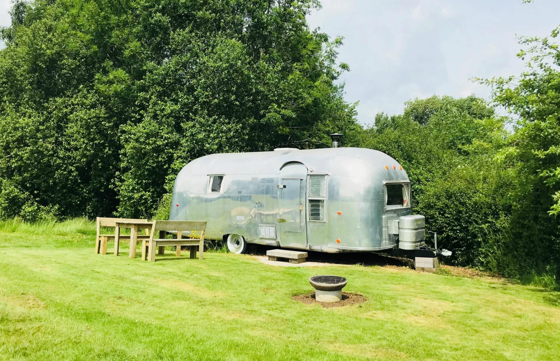 <p>Cotswold Camping benefits from an idyllic location: the site is built on the grounds of a former Norman castle and the moat is still visible. Airstream Ana, an original Silver Bullet Airstream from the 1960s, provides the perfect base. On top of central heating, it even has its own indoor log burner – it is England, after all!</p>