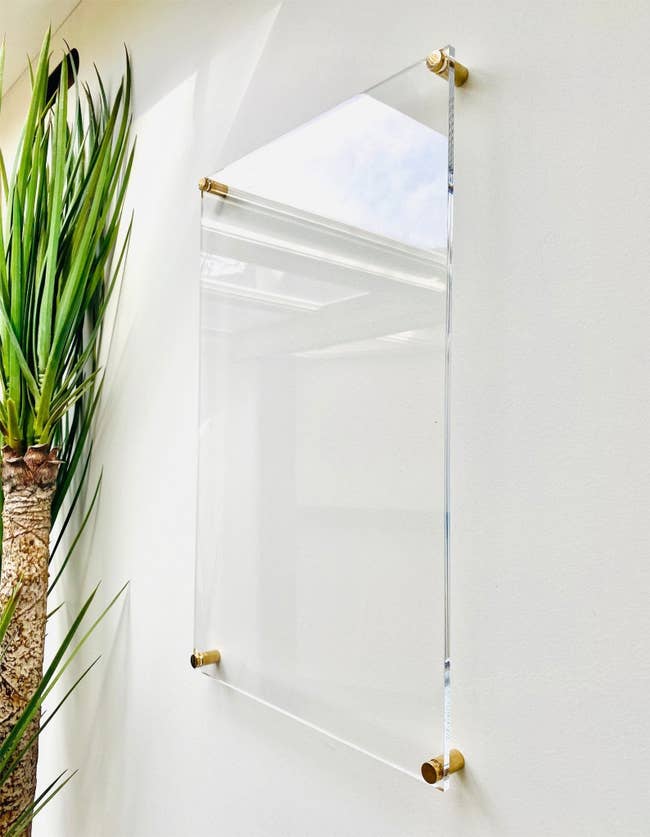 a clear acrylic white board with gold mounting hardware