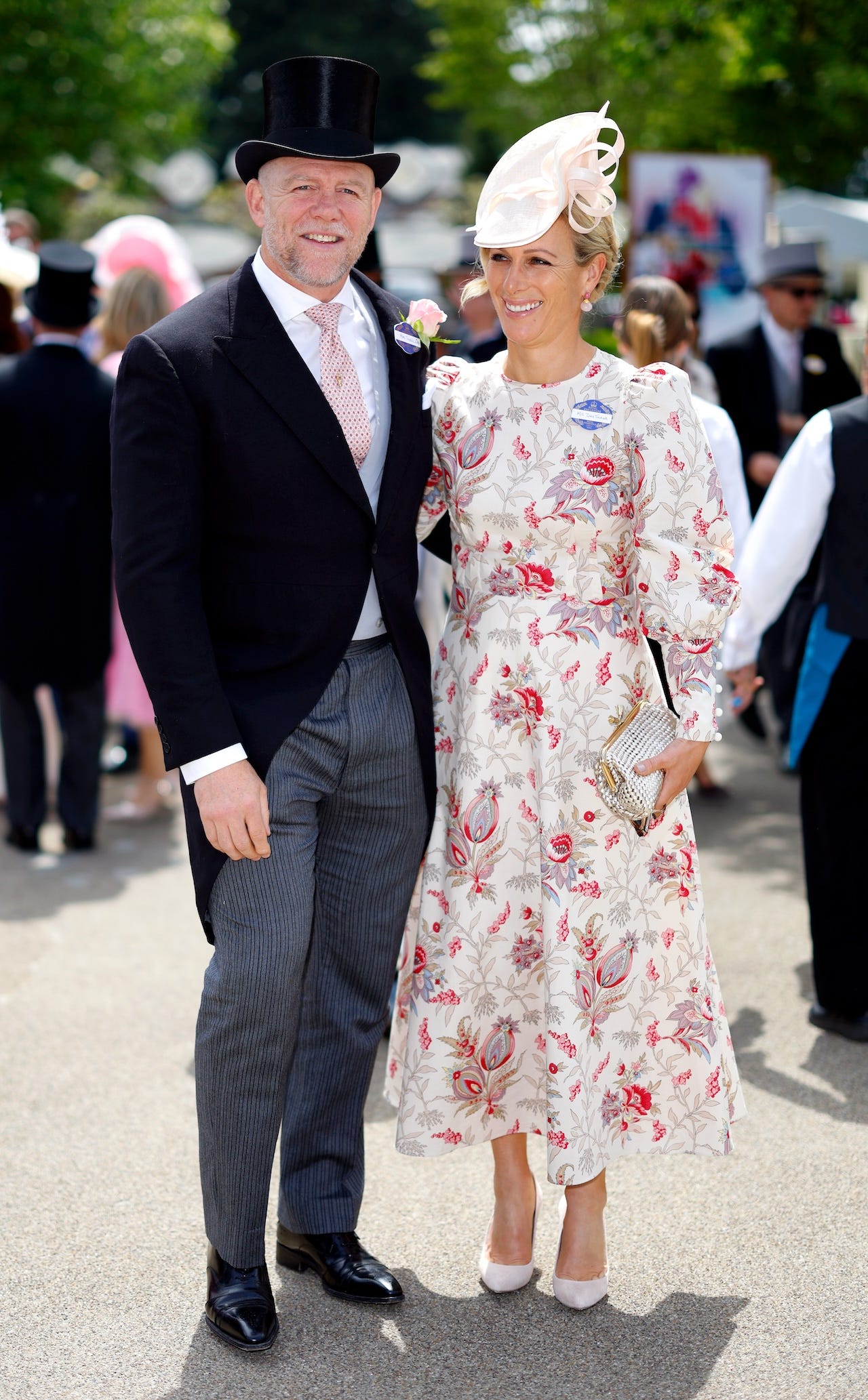 <p>Serving up another fashion masterclass for couples attending Royal Ascot, the Tindalls showed up in style on day two of the racing event.</p><p>Zara wore a white midi dress covered in red, pink, and light purple botanical prints. The $1,286 <a href="https://annamasonlondon.co.uk/products/angelika-dress-ss24?">Angelika dress</a>, designed by Anna Mason London, featured puff sleeves and long cuffs. Zara paired it with a light-pink fascinator, white pumps, and a metallic clutch in a similar shade of white.</p><p>Staying loyal to the men's dress code, Mike opted for a black morning suit jacket with gray-striped pants. He added flair to the look with a silk waistcoat, a pink tie, and a pink rose boutonnière.</p>