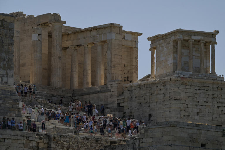 Tourists sit on the steps of the ancient Acropolis hill during a hot day in Athens on June 12, 2024.