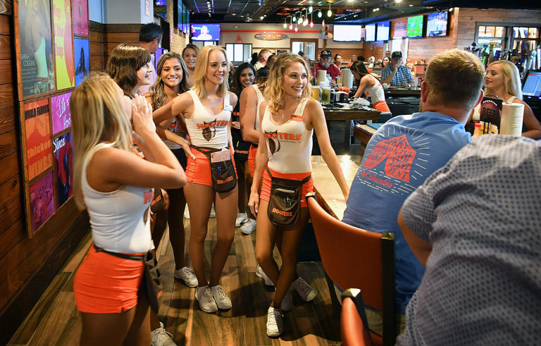 A group of Hooters Girls gather at the bar to perform a short song for a patron's birthday.